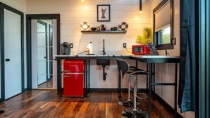 Une cuisine compacte avec un réfrigérateur rouge, un évier, un four à micro-ondes et un tabouret de bar.