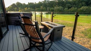 Une terrasse dotée d’une chaise berçante, d’une petite table et d’un barbecue encastré.