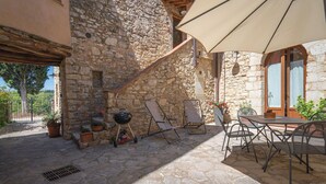 An outdoor patio with stone walls, a grill, lounge chairs, and a table with chairs. - Stunning  villa with pool, WIFI, TV, terrace and panoramic view, close to Greve In Chianti (Gaiole In Chianti)