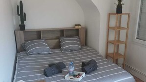 A bedroom with a bed, bedside table, and a hanging light fixture. - The Crew House Amiens (Cagny)