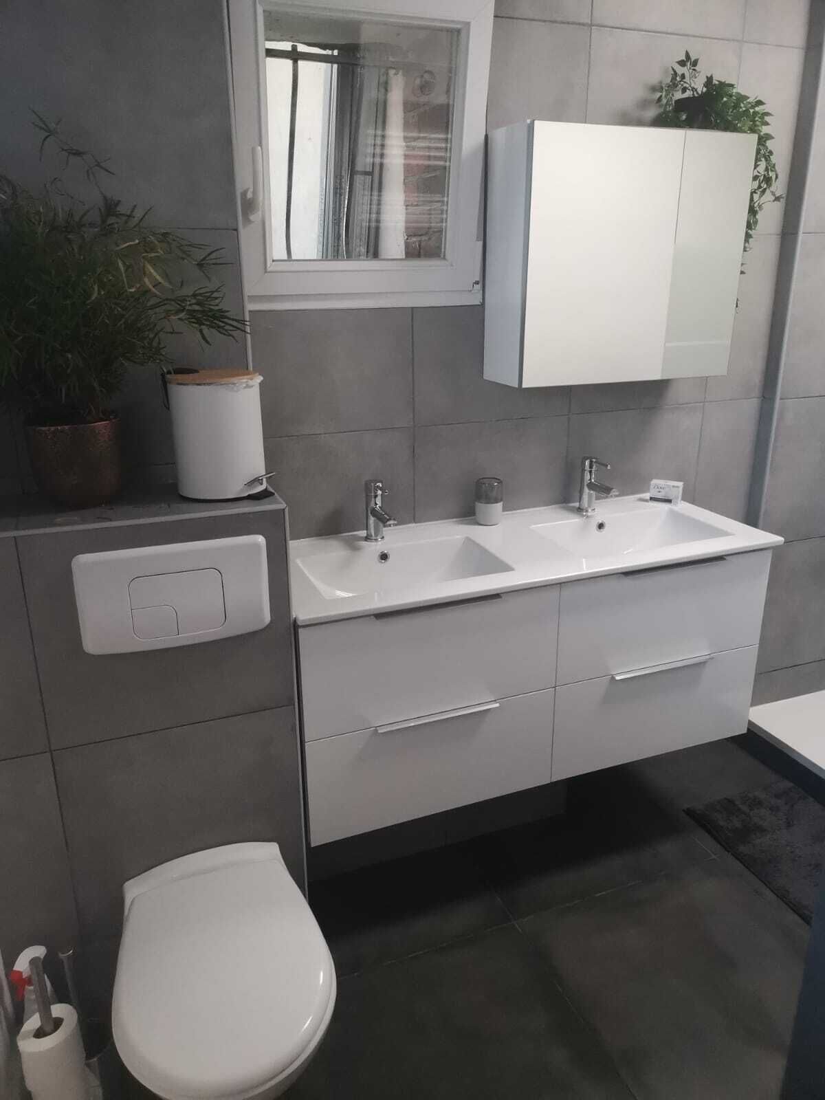 Een moderne badkamer met twee wastafels, een toilet en een spiegel boven de wastafel.