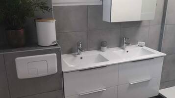 Een moderne badkamer met twee wastafels, een toilet en een spiegel boven de wastafel.
