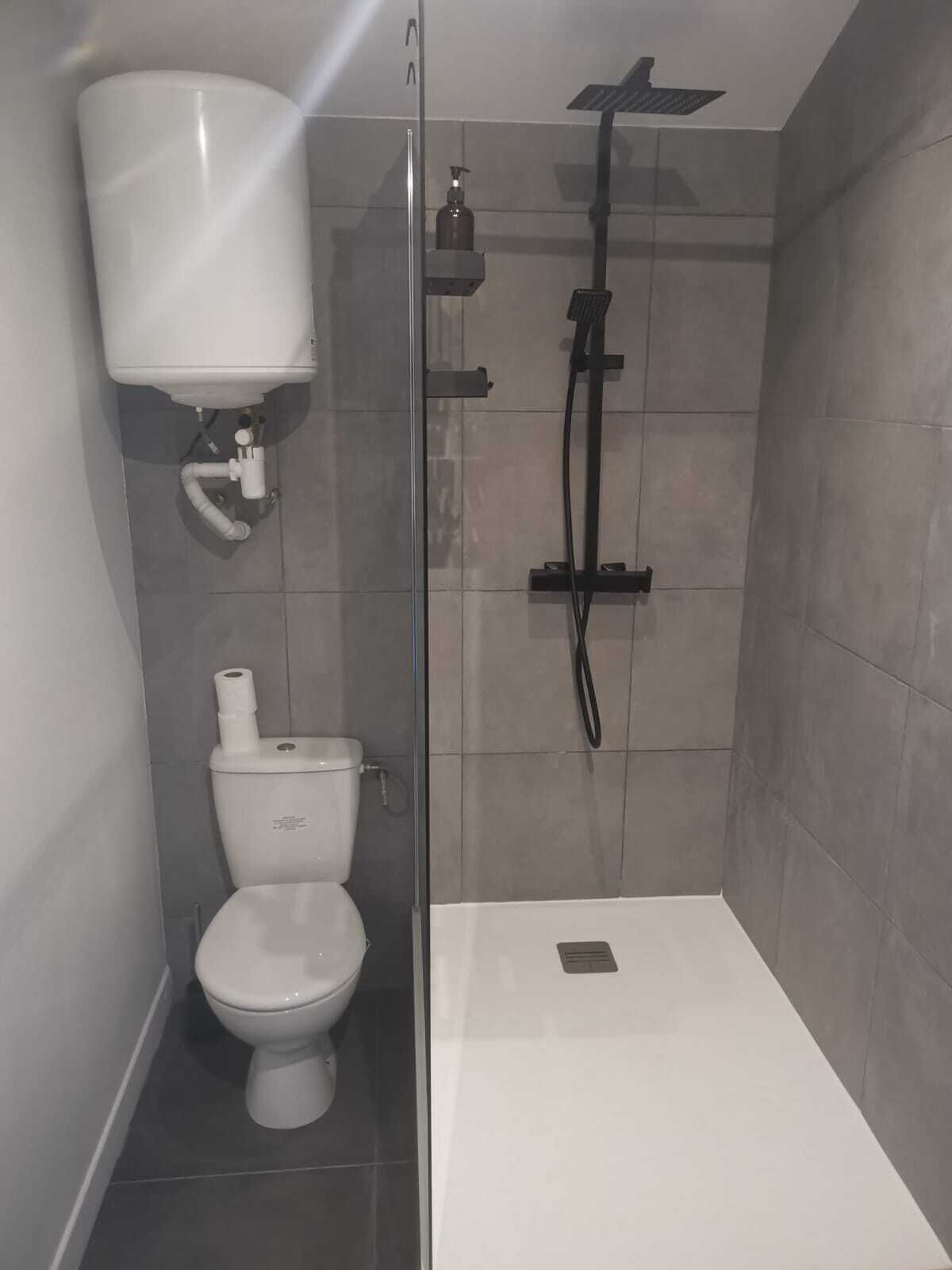 Un bagno moderno con il water, uno spazio doccia e una vasca da bagno bianca.