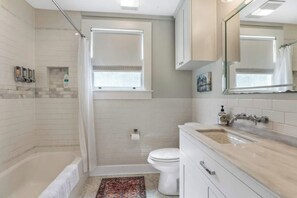 A modern bathroom with a bathtub, shower, toilet, and vanity.