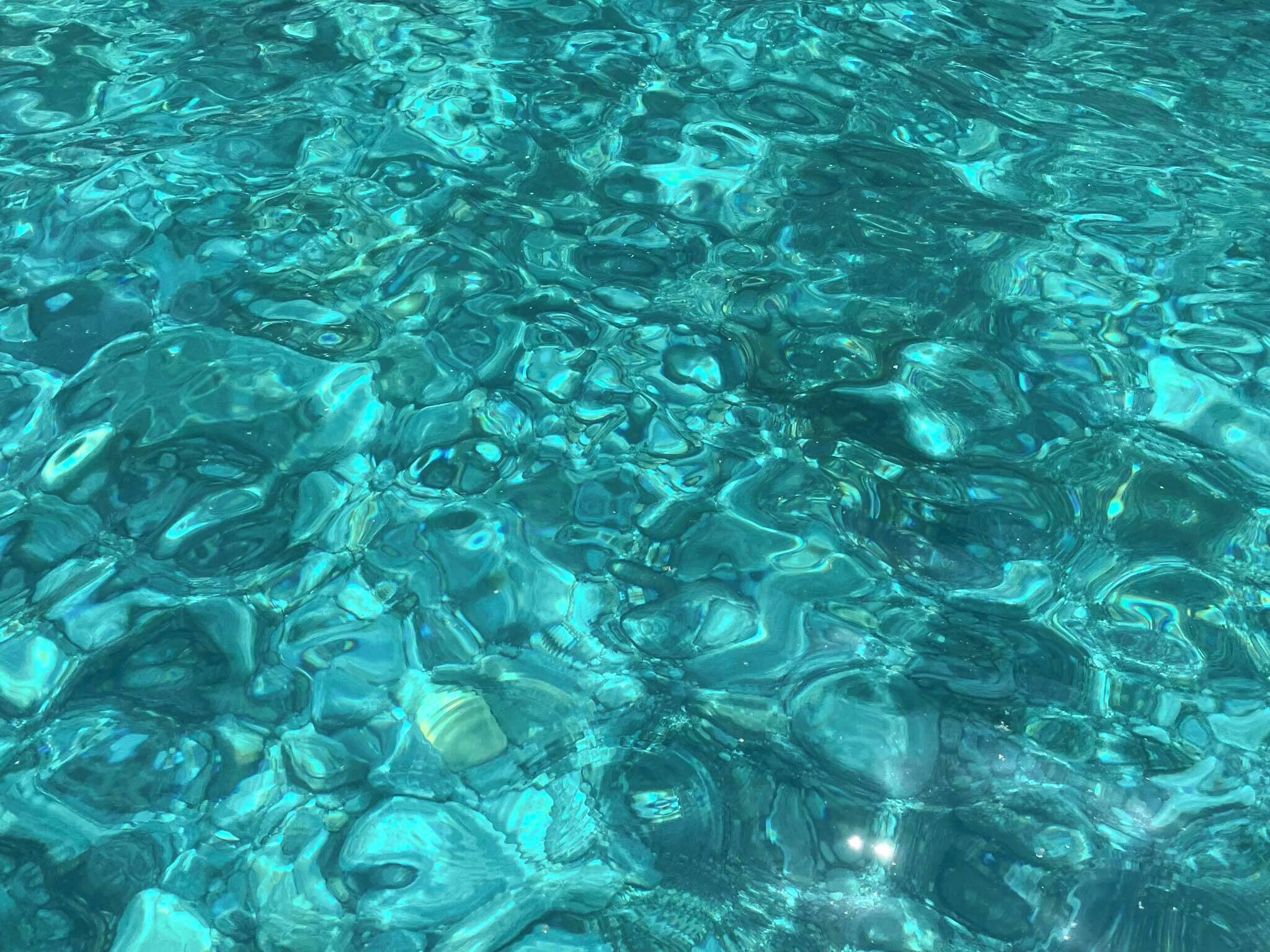 A clear, shallow water body with a rocky bottom, likely a pool or a lake.