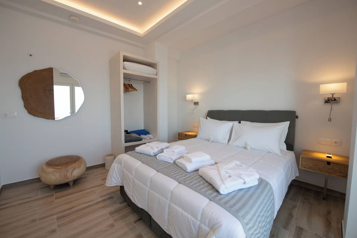 Une chambre à coucher moderne avec un grand lit, un dressing et un grand miroir rond accroché au mur.