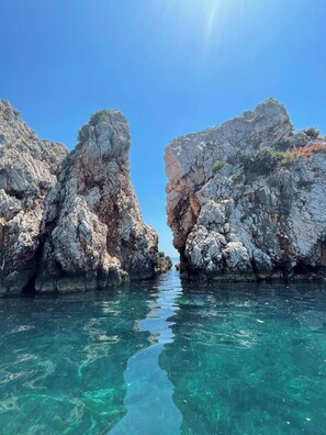 A rocky coastline with clear water between two large rock formations. - Flisvos Beachfront Apartments (Skopelos)