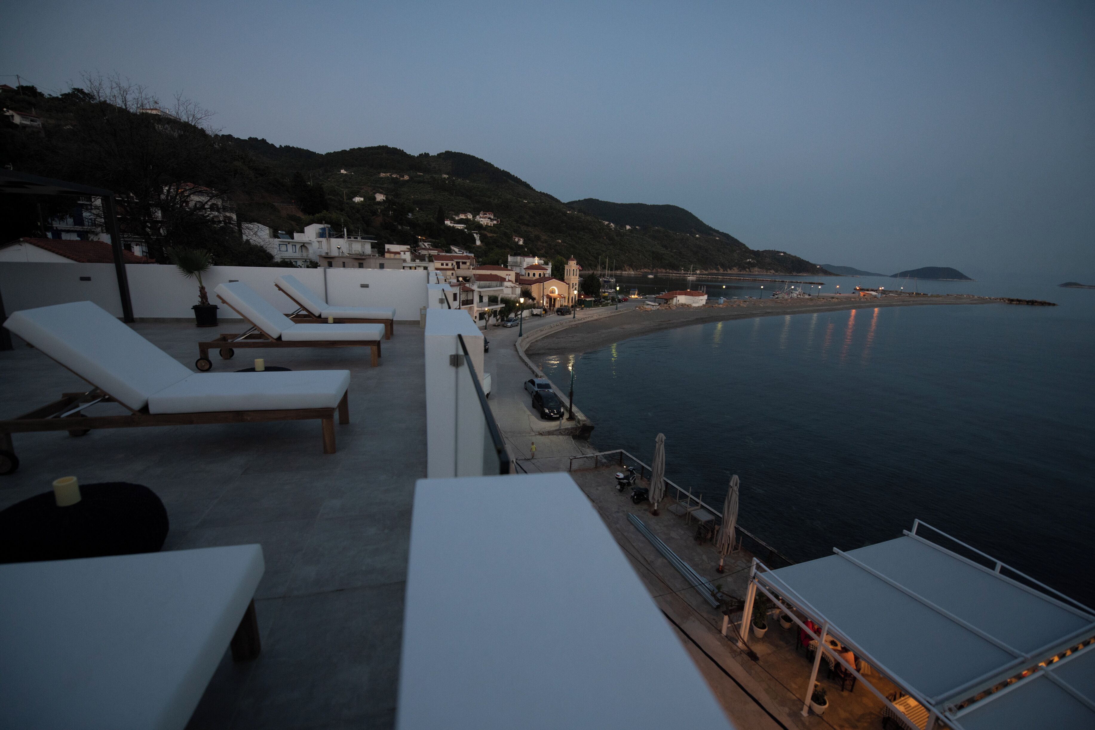 A seaside terrace with lounge chairs, a pool, and a view of the beach and sea.