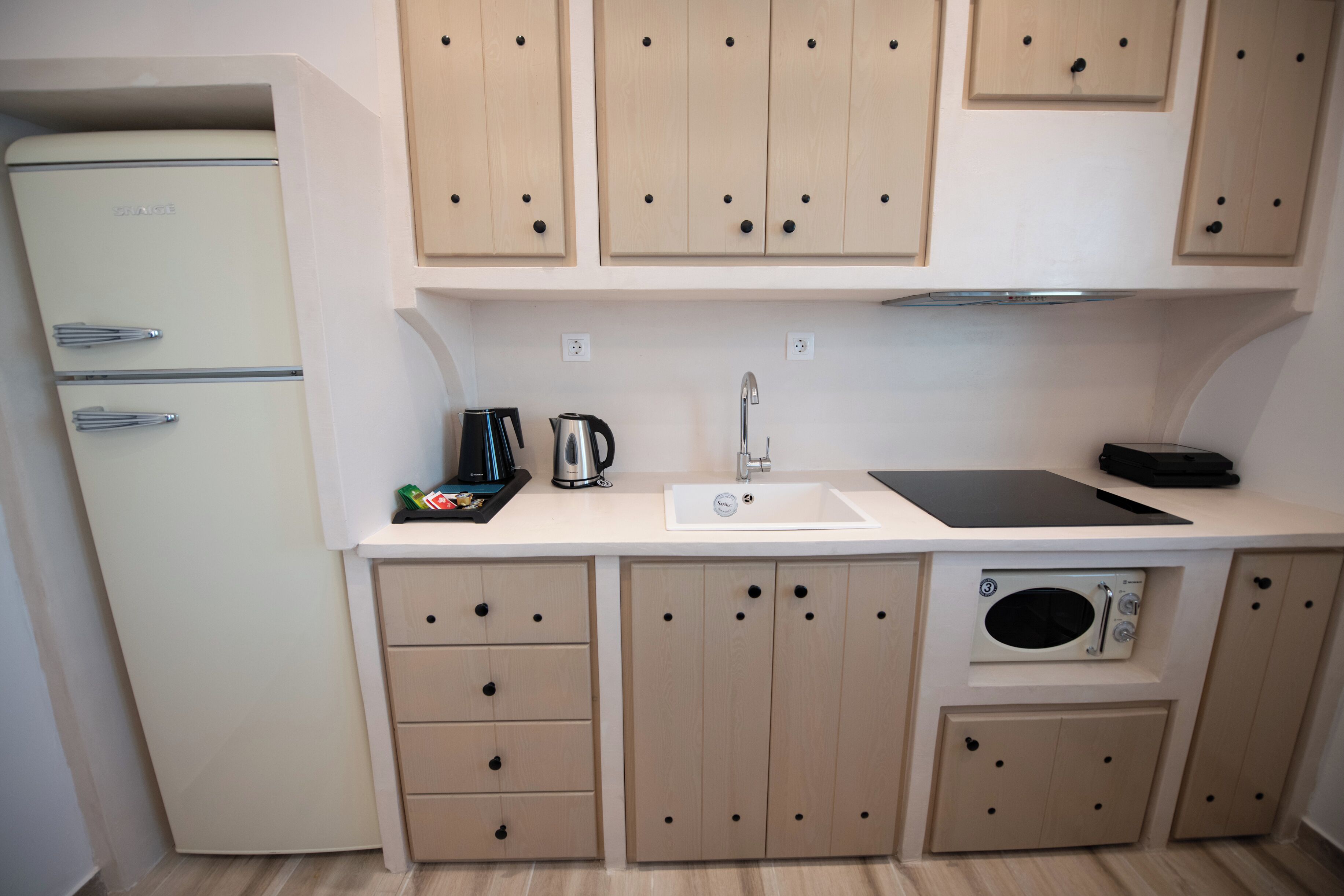 Una cocina compacta con refrigerador, lavaplatos, estufa y alacenas.