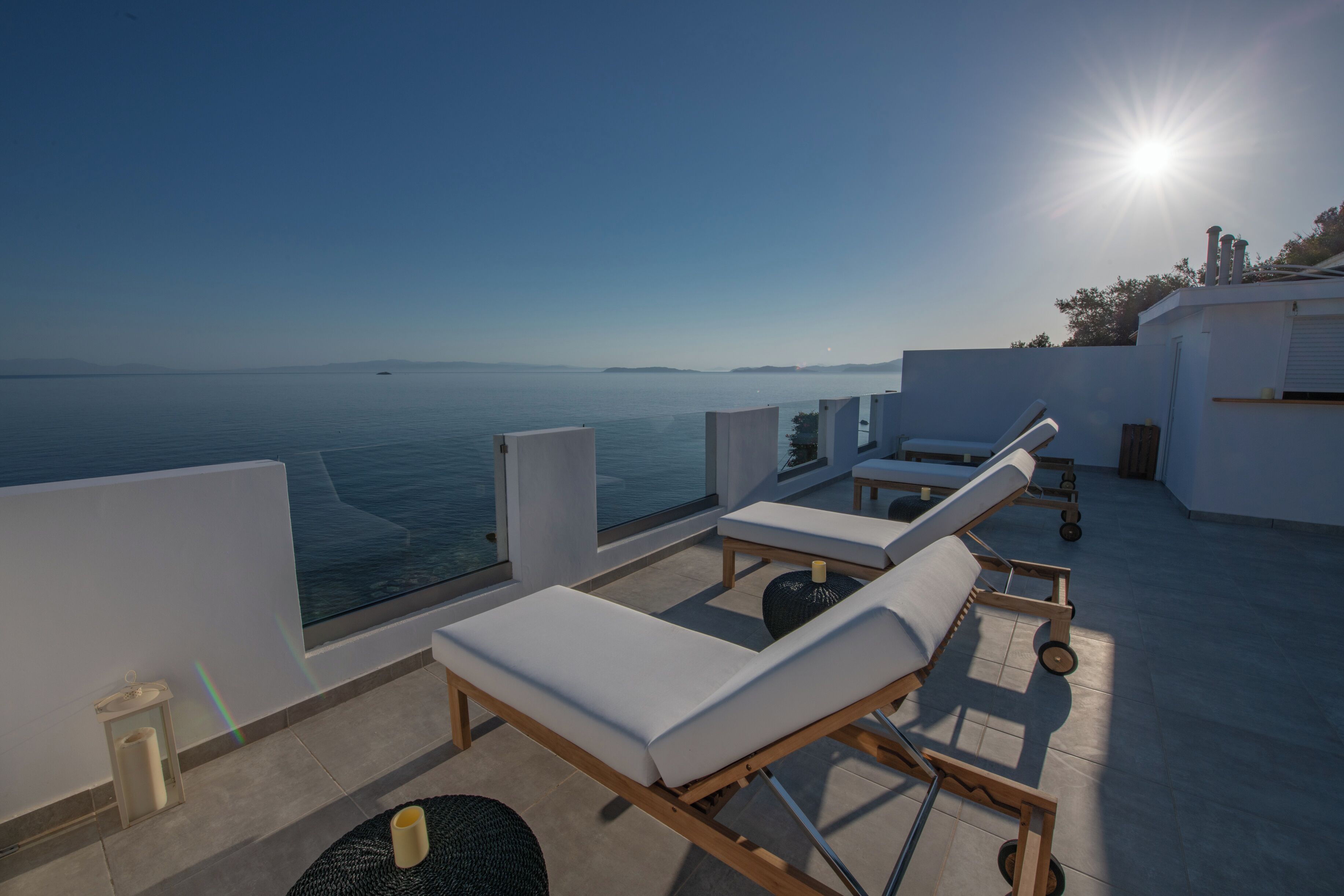 Una terraza en la azotea con sillones de sol, vista al mar y cielo despejado.