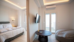 Ein modernes Hotelzimmer mit Bett, rundem Tisch, Sitzsack und einem an der Wand montierten Fernseher.