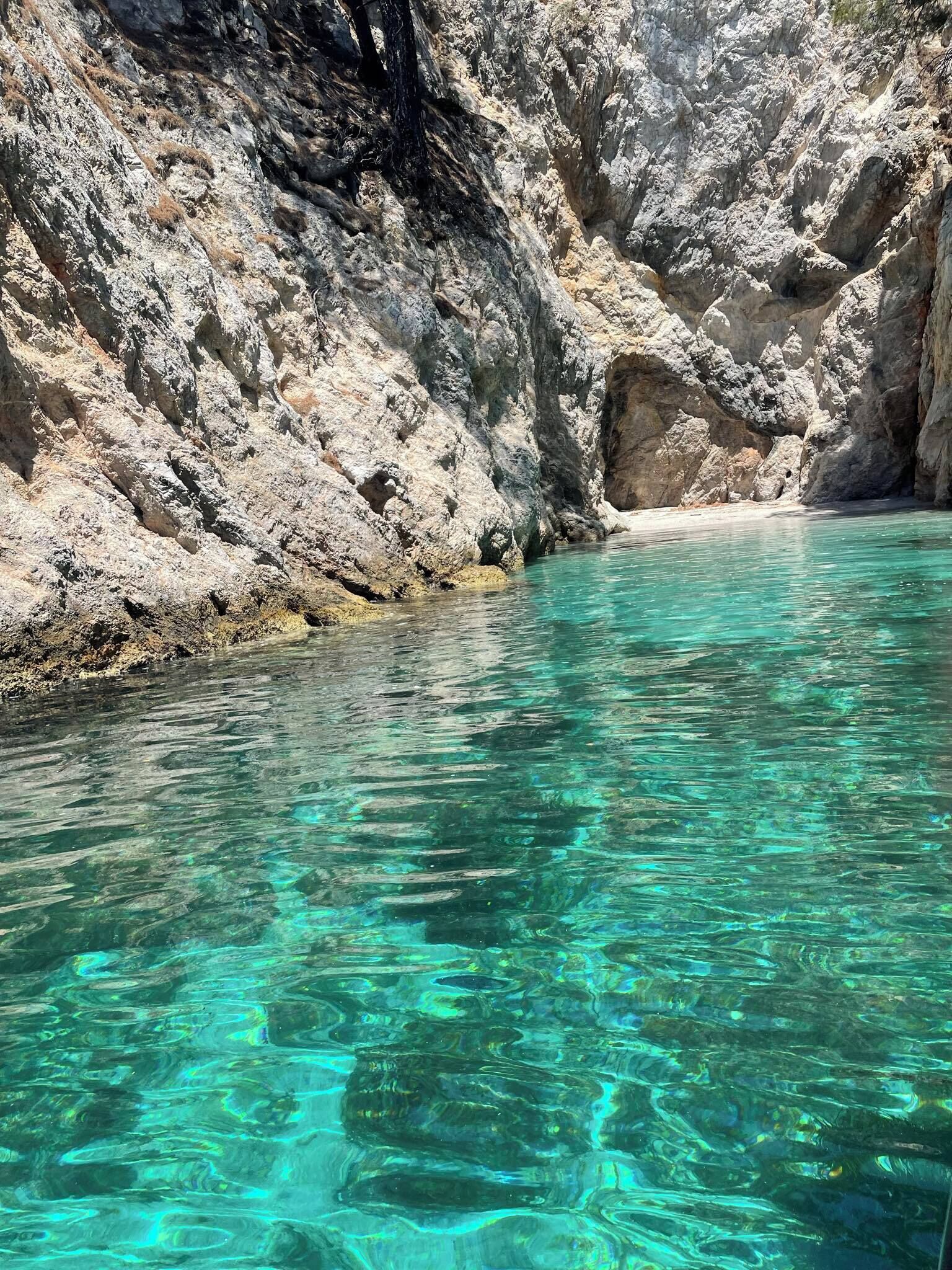 Une mer d’un bleu turquoise limpide, bordée de falaises rocheuses.