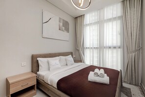Ein ordentlich gemachtes Bett mit einer braunen Decke, ein Nachttisch mit Schublade und eine an der Wand befestigte Lampe.