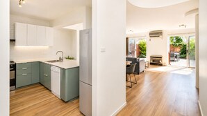 A modern kitchen with white cabinets, a built-in dishwasher, and a stainless steel refrigerator. - Abby's Beach Villa (Broadwater)