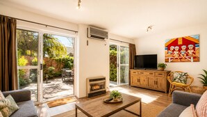 A living room with a sofa, a coffee table, a TV, and a fireplace. - Abby's Beach Villa (Broadwater)