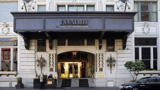 Exterior del hotel Roosevelt Waldorf Astoria, con una entrada imponente, escalones que conducen a las puertas y un letrero destacado sobre la entrada.