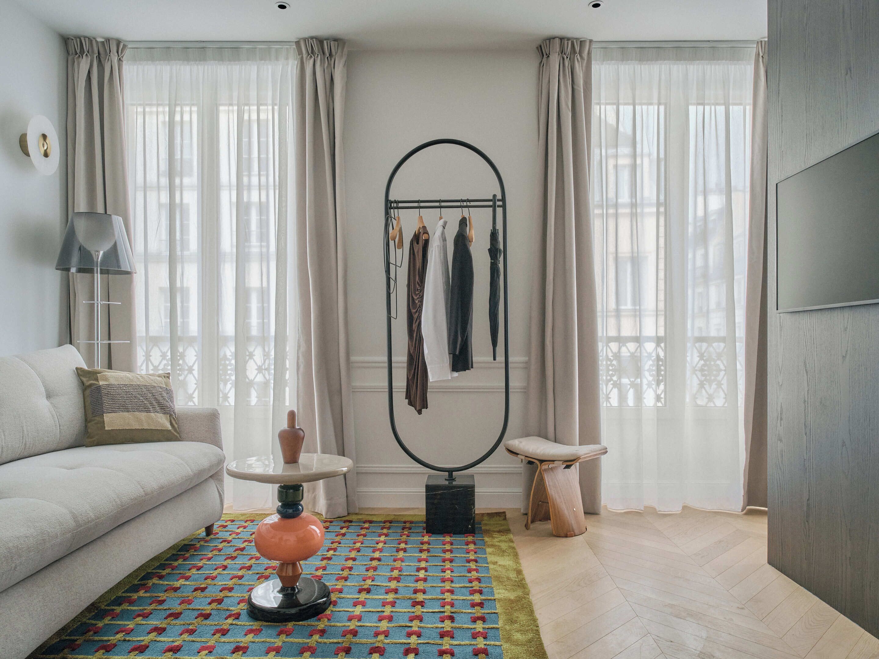 A modern living room with a sofa, a round mirror, a small table, and a patterned rug.