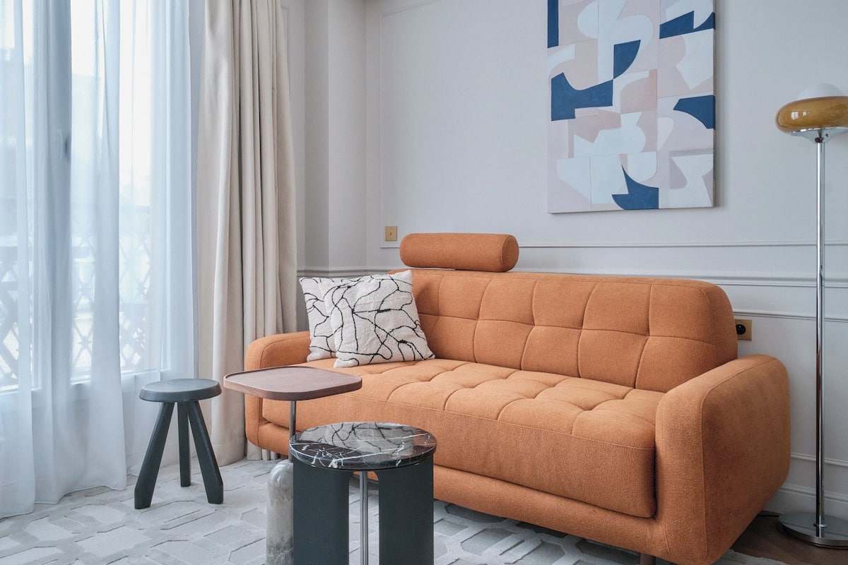 A modern living room with a sofa, a small round table, and a floor lamp.