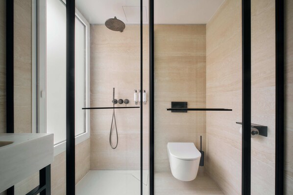 Un baño moderno con cabina de ducha de vidrio, inodoro blanco y diseño minimalista.