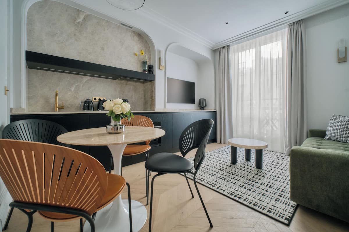 A modern living room with a green sofa, a round coffee table, and a dining area with a round table and chairs.