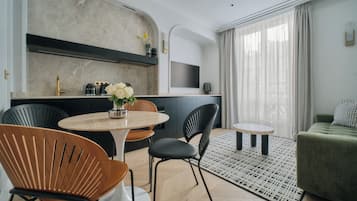 Un salon moderne avec un canapé vert, une table basse ronde et un coin repas comprenant une table ronde et des chaises.