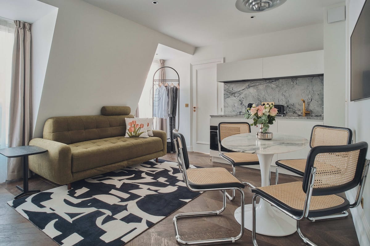A modern living room with a sofa, a coffee table, and a dining area with chairs.