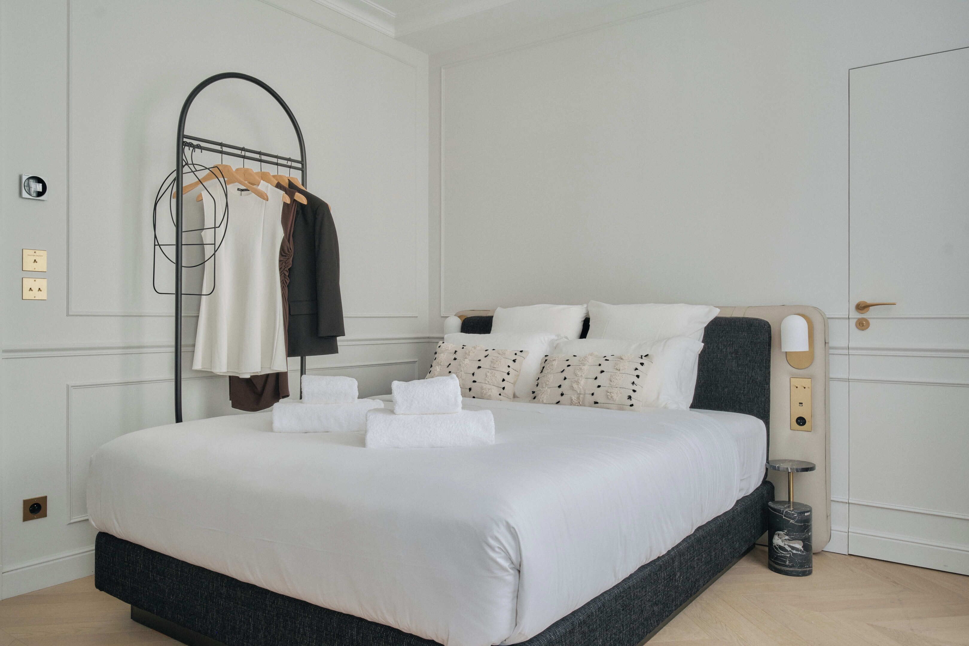 A neatly made bed with white linens, a wooden headboard, and a bedside table with a lamp.