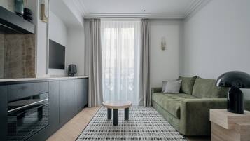 A modern living room with a green sofa, a round coffee table, and a black lamp.