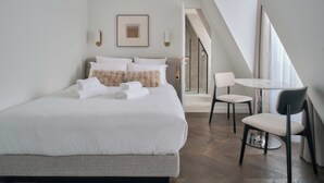 A modern bedroom with a large bed, a small table, and chairs. - Nestay Les Halles (Paris)