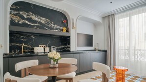 A modern kitchen with a marble backsplash, a round wooden table, and white chairs. - Nestay Les Halles (Paris)
