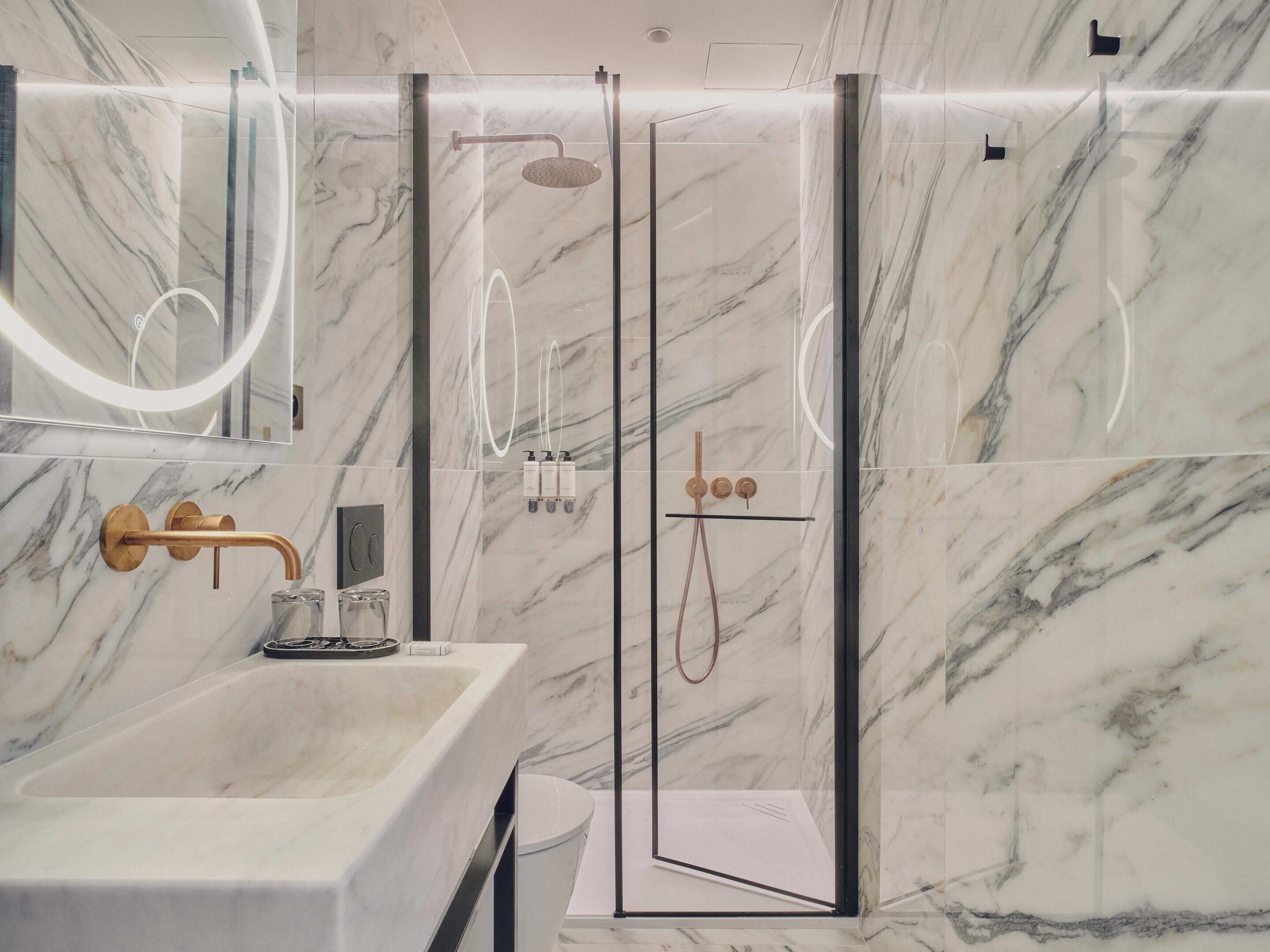 Un bagno moderno con un lavabo in marmo, una cabina doccia in vetro e uno specchio grande.