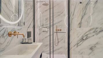 Un bagno moderno con un lavabo in marmo, una cabina doccia in vetro e uno specchio grande.