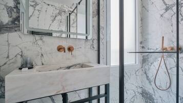 A bathroom with a marble sink, a mirror, and a shower with a glass door.