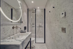 A modern bathroom with a marble sink, a glass-enclosed shower, and a wall-mounted thermostat. - Nestay Les Halles (Paris)