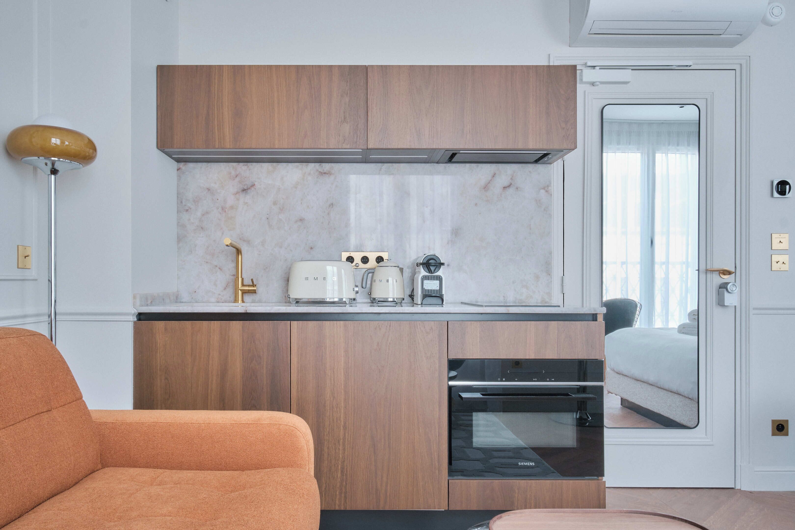 Una cocina compacta con armarios de madera, horno empotrado y cafetera.