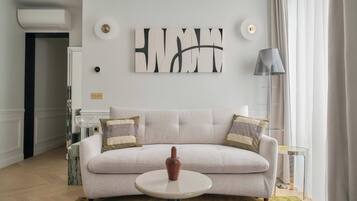 Un salon avec un canapé beige, une table basse ronde et un tapis coloré.