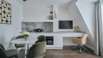 Una cocina moderna con armarios blancos, encimera de mármol y televisor integrado.