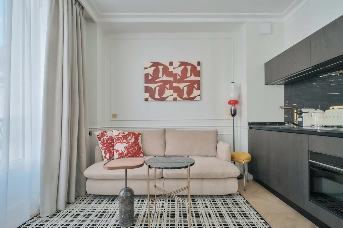 A modern living room with a sofa, a small round table, and a decorative lamp.