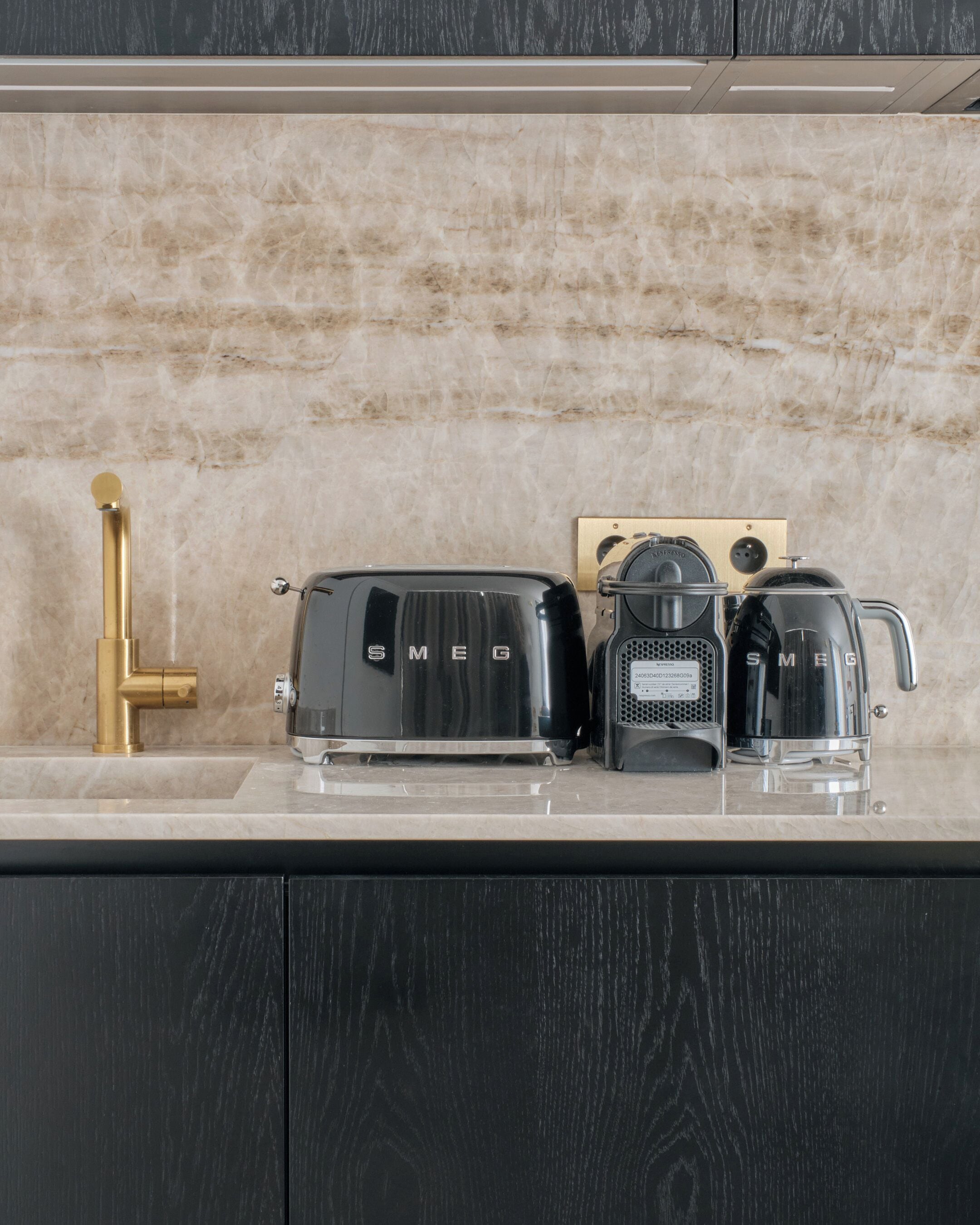 Un comptoir de cuisine avec un robinet doré, un grille-pain, une machine à café et un four à micro-ondes.