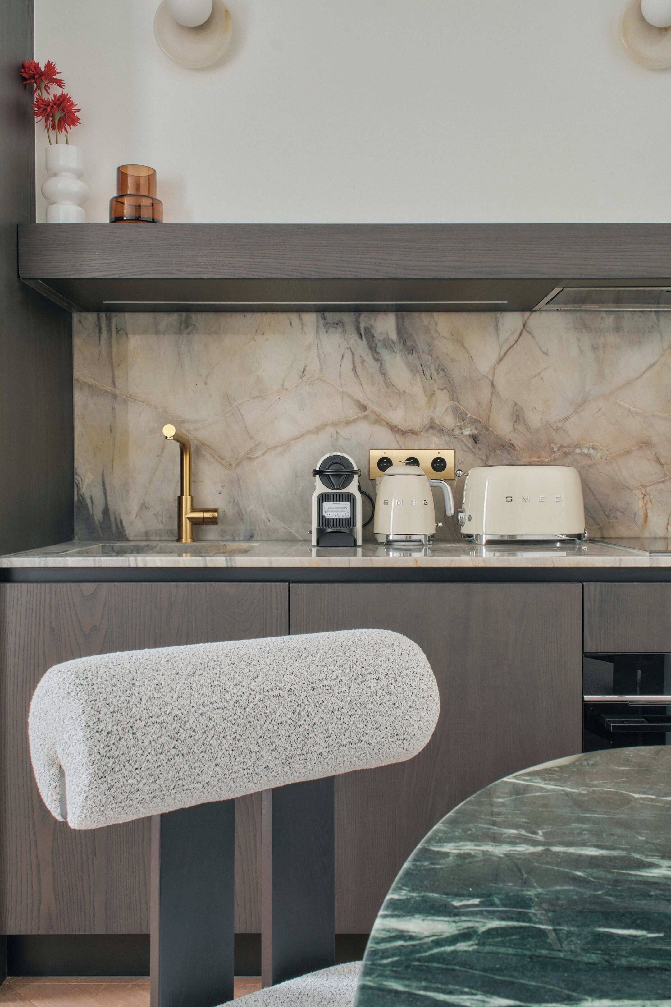 A kitchen with a marble backsplash, a sink, a coffee maker, and a toaster.