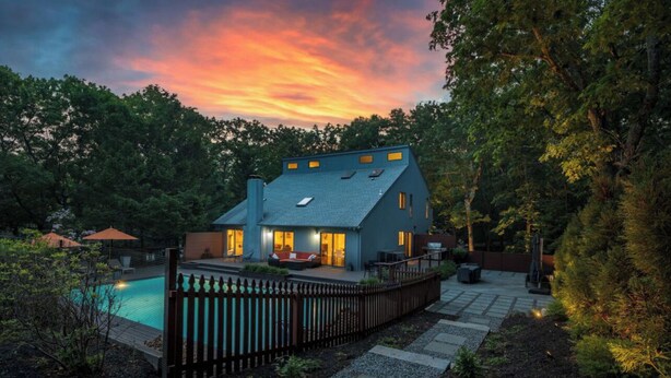 Une maison avec une piscine, entourée d’une clôture en bois et d’un jardin.