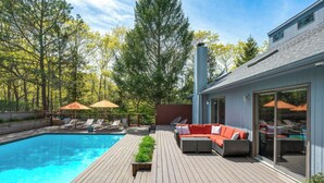 Une maison moderne dotée d’une terrasse en bois, d’une piscine et d’un espace salon extérieur.