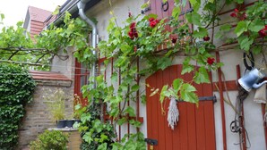 A red door with a lock, a metal watering can, and green foliage. - Blüten Remise - Welcome to the flower city of Werder! (Werder (Havel))