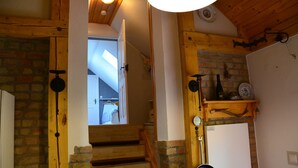 A wooden staircase with brick walls, a hanging pot, and a white door leading to another room. - Blüten Remise - Welcome to the flower city of Werder! (Werder (Havel))