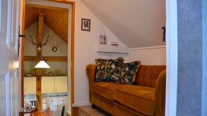 A cozy living room with a brown sofa, a coffee table, and a kitchen visible in the background. - Blüten Remise - Welcome to the flower city of Werder! (Werder (Havel))