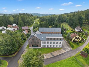 An aerial view of a residential area with a large two-story house featuring a modern design, surrounded by lush greenery and a winding road. - Javorná Lodge by Interhome (Javorná)