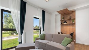 A modern living room with a sofa, a coffee table, and a wooden shelving unit against a white wall. - Javorná Lodge by Interhome (Javorná)