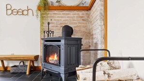 A room with a fireplace, a bench, and a wall-mounted sign that reads 'Beach.' - Sand Cove Cottage-New! (Gouldsboro)