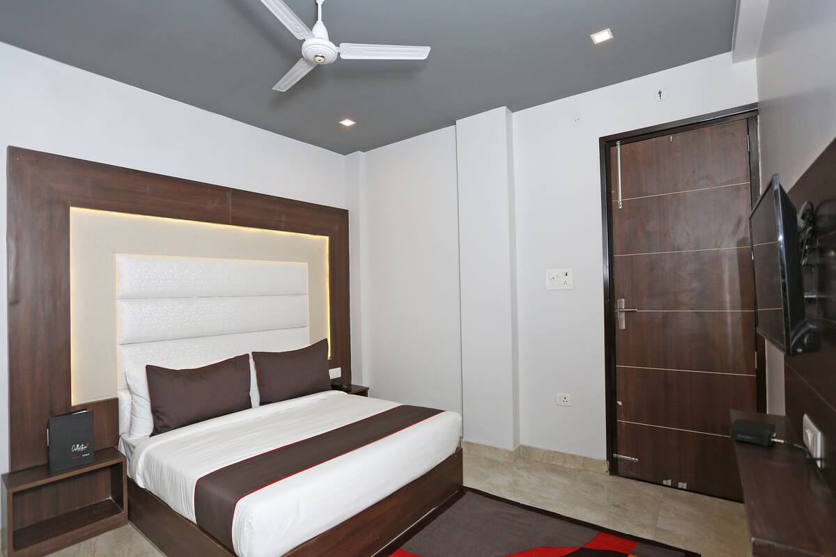 Una habitación de hotel moderna con una cama grande, un ventilador de techo, un armario de madera y una televisión.