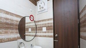 A bathroom with a white sink, a mirror, and a towel rack. - Hotel Arhaan Palace By GRB (New Delhi)